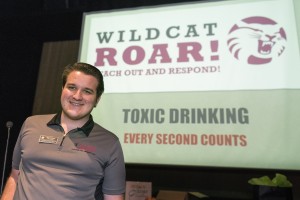 Peer Educator Evan Thibeau pictured with a powerpoint presentation on alcohol poisoning and substance abuse.