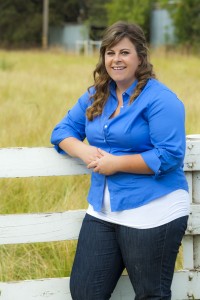 Holly Hockett posed leaning on a white picket fence at the Univesity Farm, with green pastures in the background 