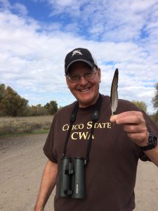 Biology professor Jay Bogiatto holds a Eurasian Wigeon feather.