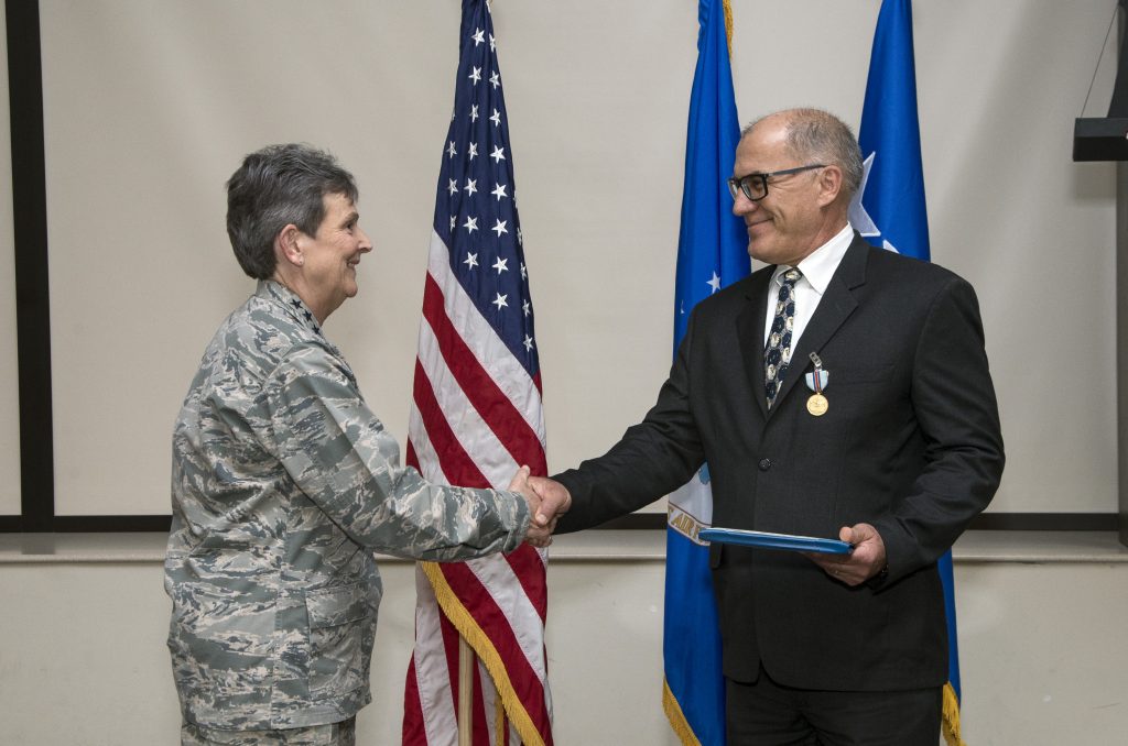 Gen. Ellen Pawlikowski shakes hands with Greg Gangnuss after presenting him with the Air Force Civilian Award for Valor.