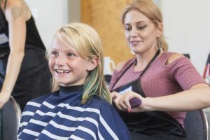 A child gets their hair cut by a woman as part of the services offered to families experiencing homelessness.