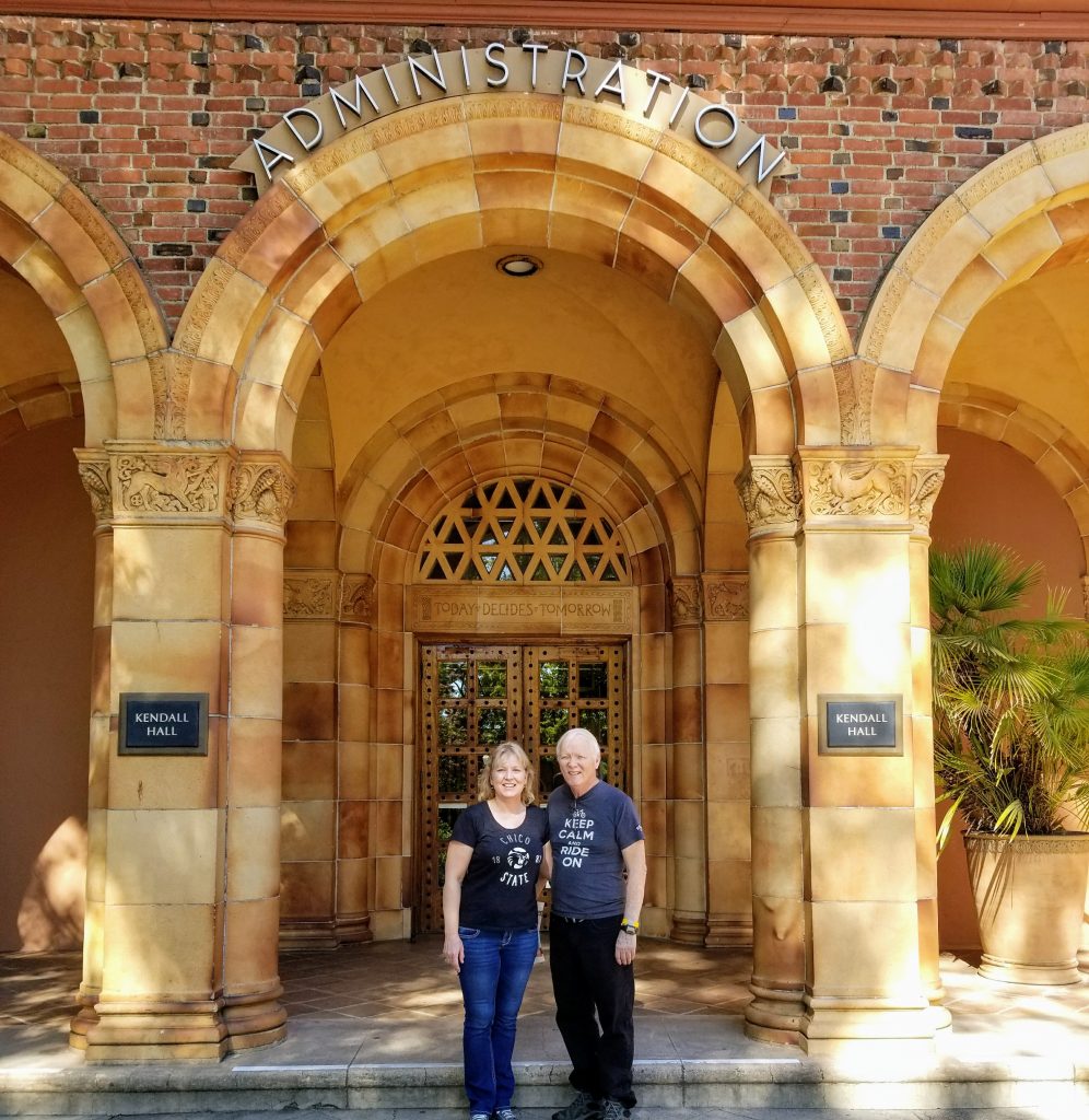 Corina Yetter and her father stand in front of the Kendall Hall main entrance archway, under a sign that says Administration