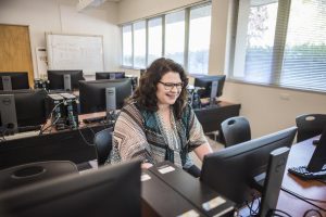 Elizabeth Konecny smiles as she works at a computer.