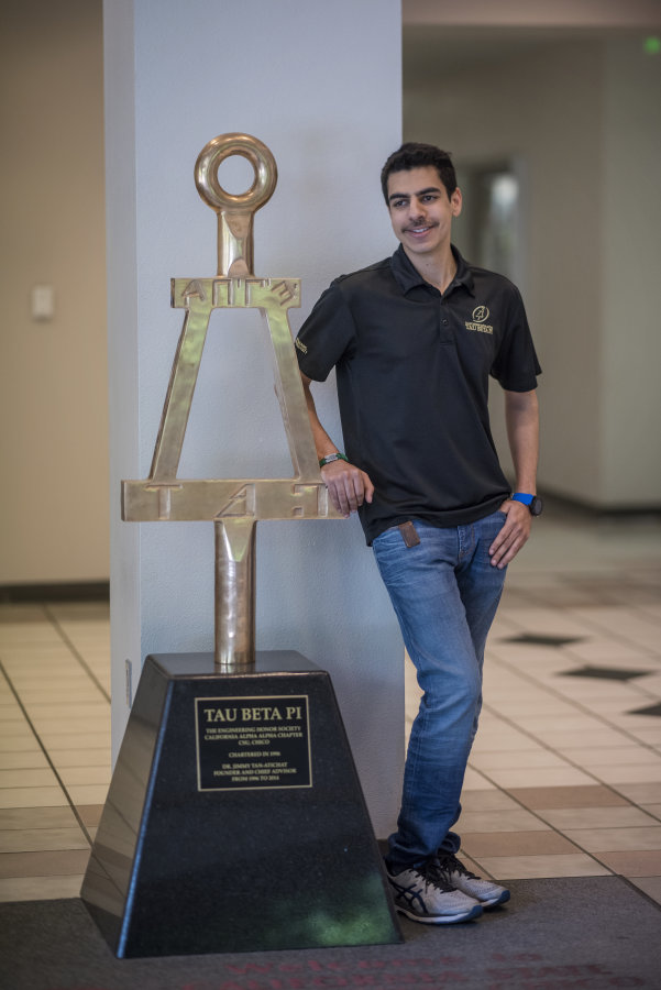 Alhumaidi stands in front of the Tau Beta Pi award on campus.