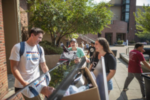 Students smile as they wait with their move-in bins