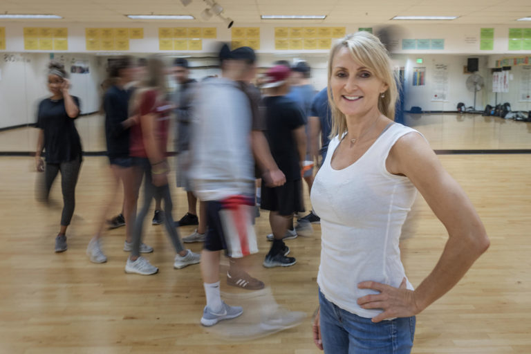 Cathrine Himberg poses while her students move in a blur in the background