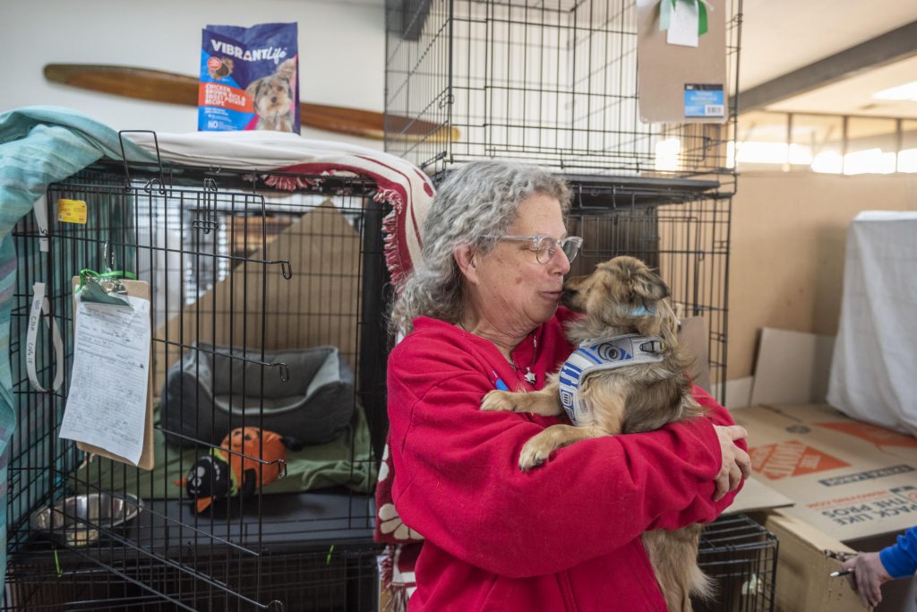 Jeanne Clark gets kisses on the face from a small dog in her arms.