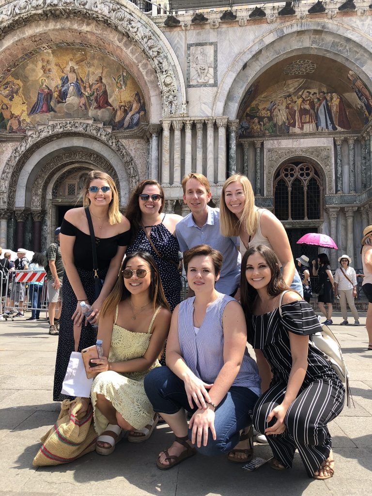 A professor and his students pose in a busy public square in Verona, Italy.