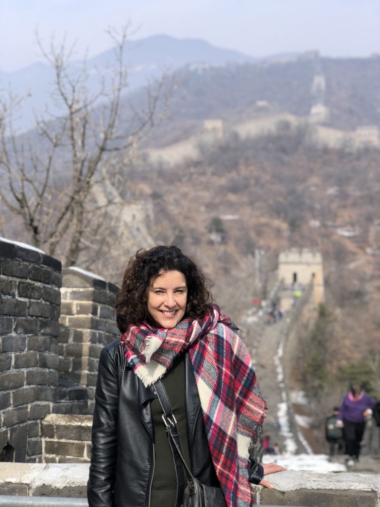 A woman stands at the Great Wall of China, bundled up in the winter.