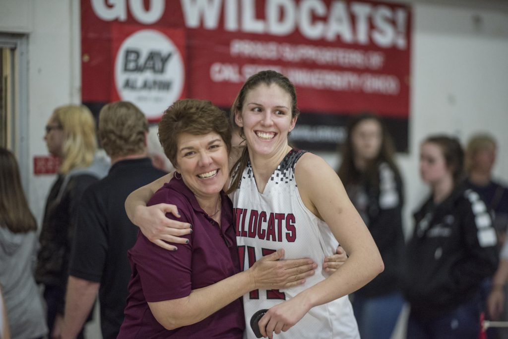 Anita wraps her arms around her daughter, who is wearing a Wildcats basketball jersey after a game.
