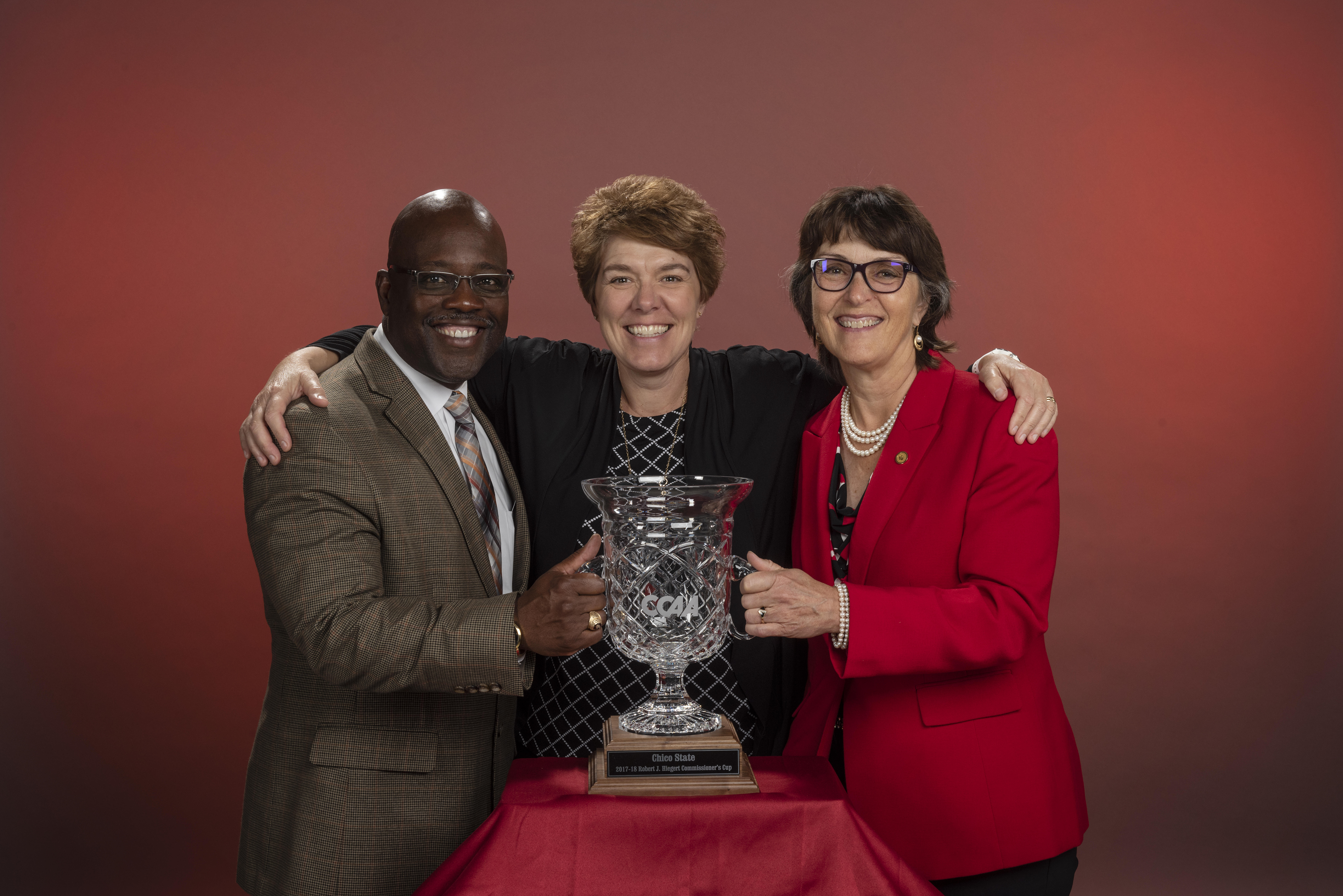 Anita stands behind the cut-glass trophy with one arm each around Milton Lang and Gayle Hutchinson.