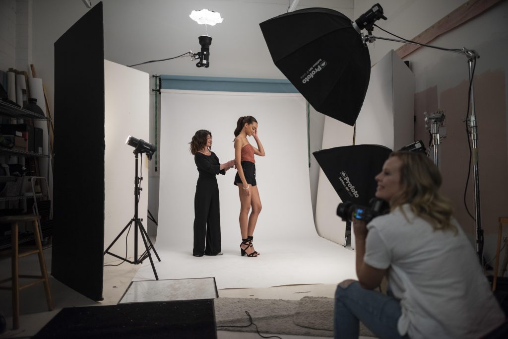 Debra Cannon makes adjustments to a model's clothes during a fashion photo shoot.
