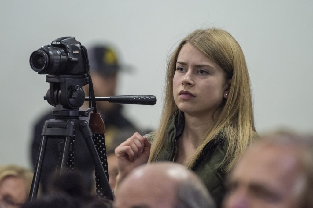 Olyvia Simpson looks through a video camera at a press conference.