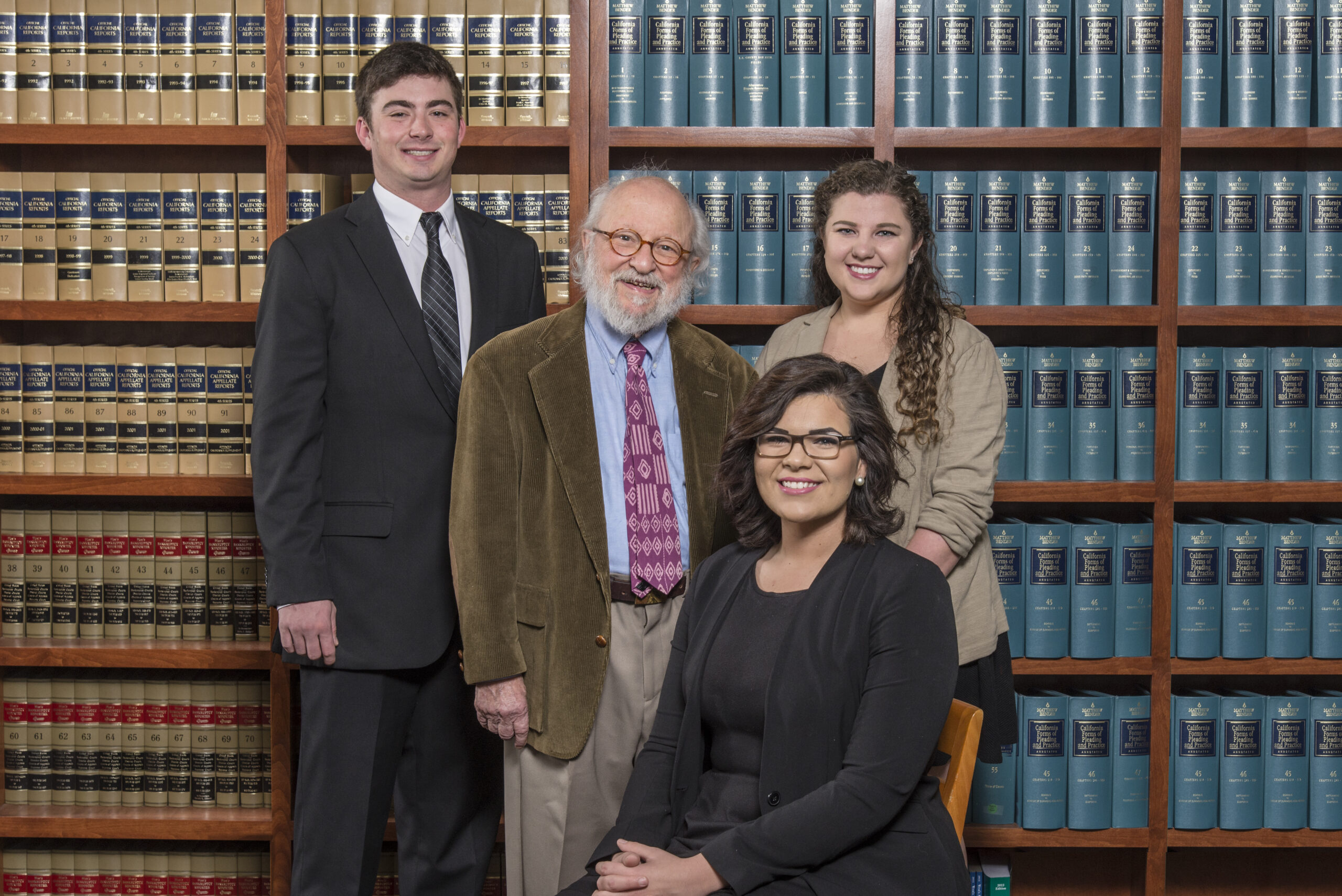 Program founder Edward Bronson with students who run the legal clinic, pictured behind legal text books.