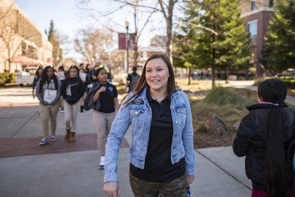 Kelsea Kennedy leads a group of high school students across the First Street Promenade on campus as part of a tour.
