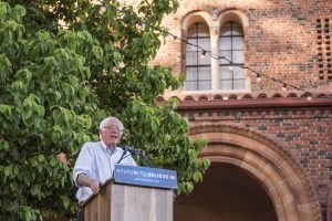 Bernie Sanders speaks at a podium in front of Laxson Auditorium.