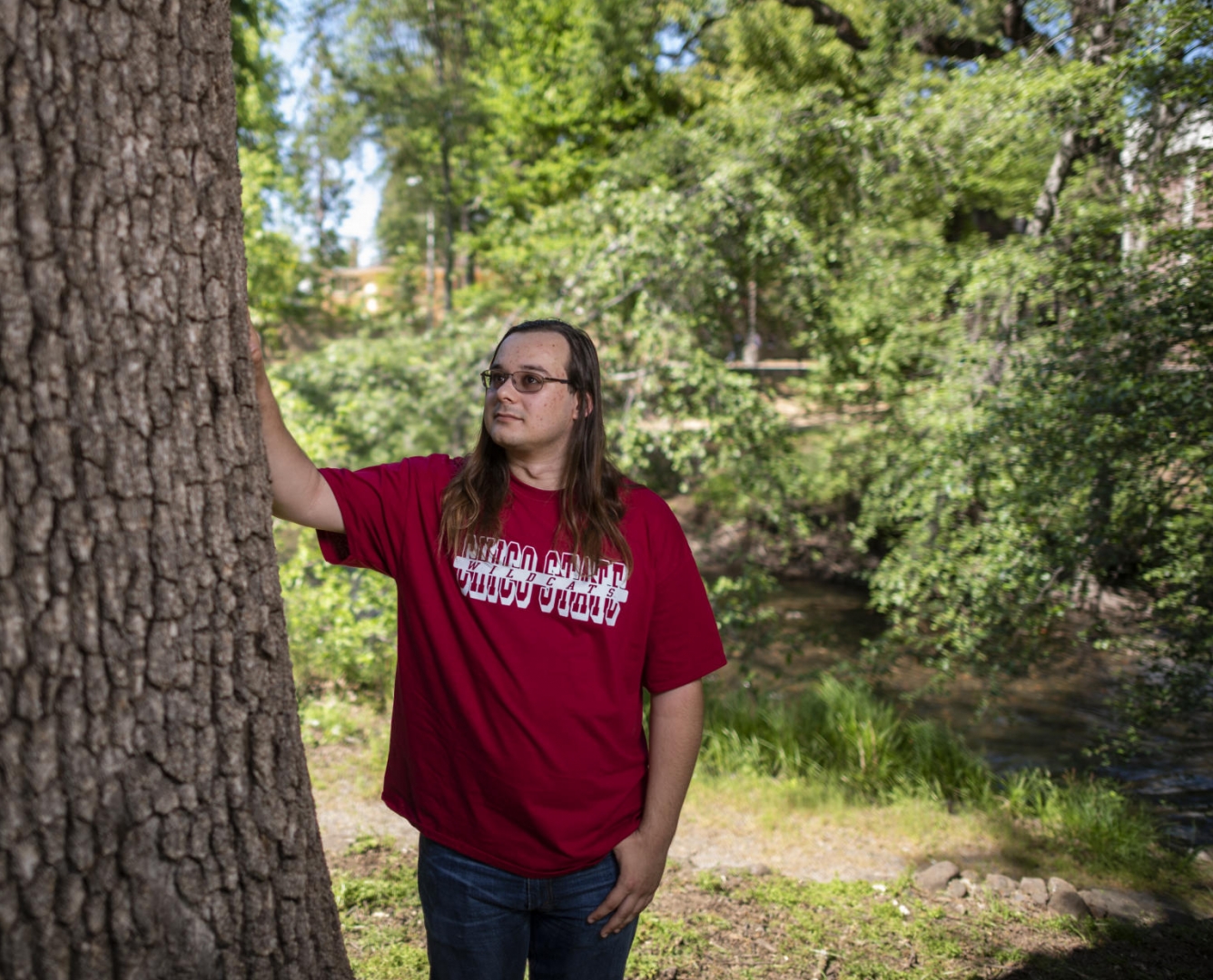 He-Lo Ramirez stands with his hand on a valley oak tree trunk near the waters of Big Chico Creek.