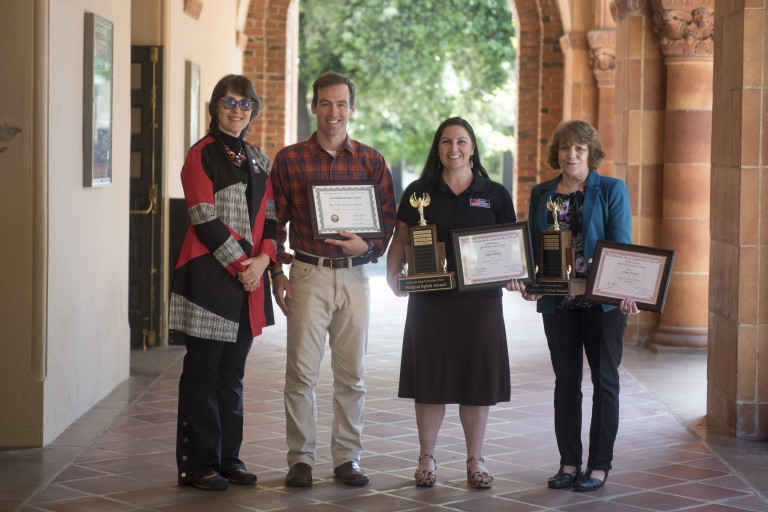 President Gayle Hutchinson stands with staff award winners Keith Crawford, Katie Sibley and Flora Nunn, each holding a plaque and trophy.
