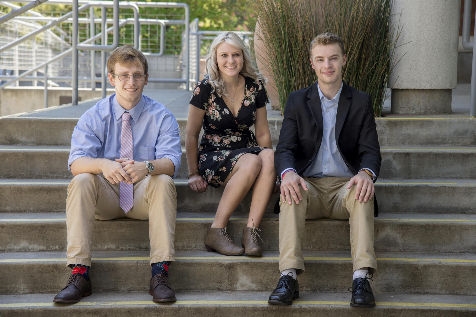 Blake Northam, Camille Davis, and Aaron Bursten sit on the stairs of the BMU.