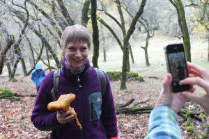 Dori Wall, a faculty member in the School of Education, poses with a jack-o'-lantern mushroom so someone can take her picture.