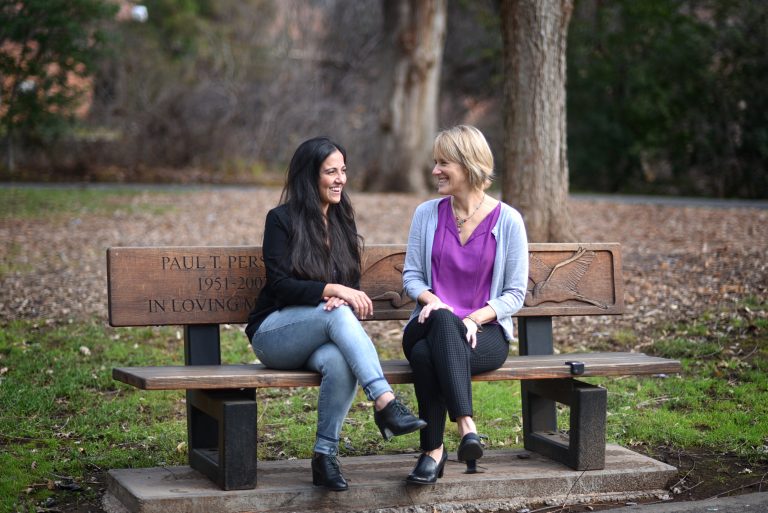 Professor Susan Roll (right) sits on a bench at CSU, Chico with her former student, Mona Kazemi (left).