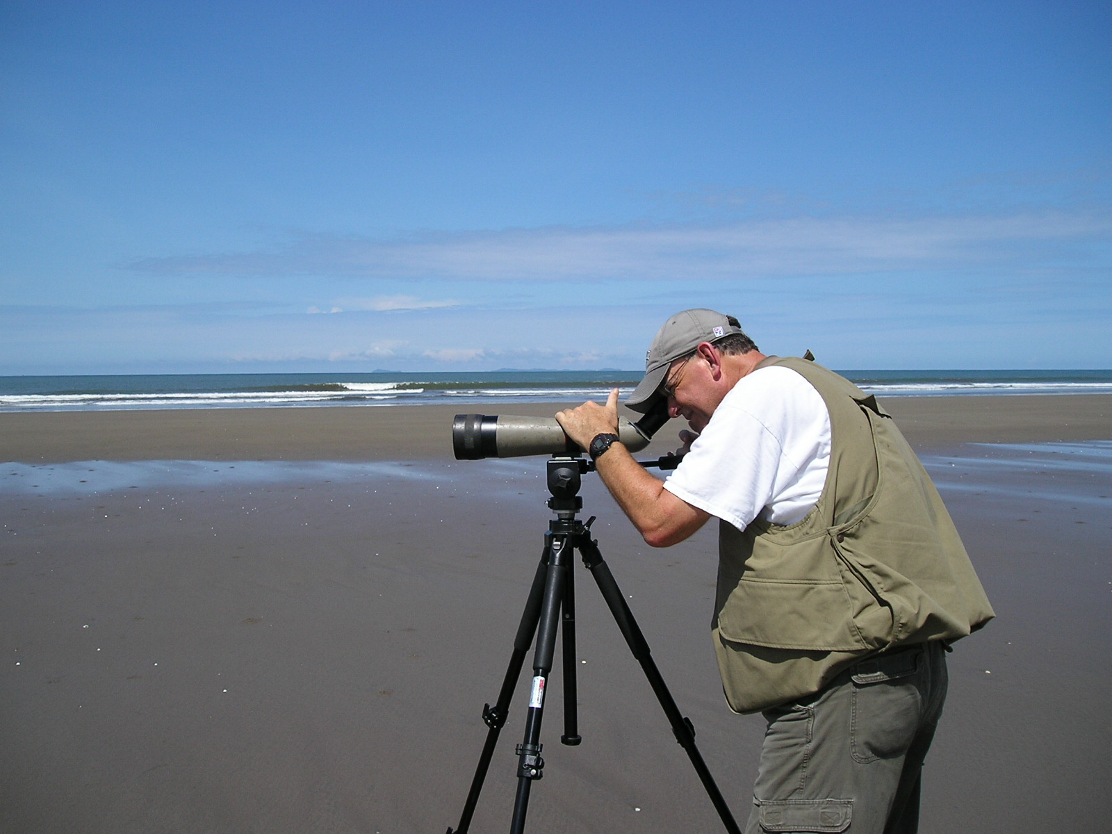 Jay Bogiatto watches birds through a scope on a beach in Panama.