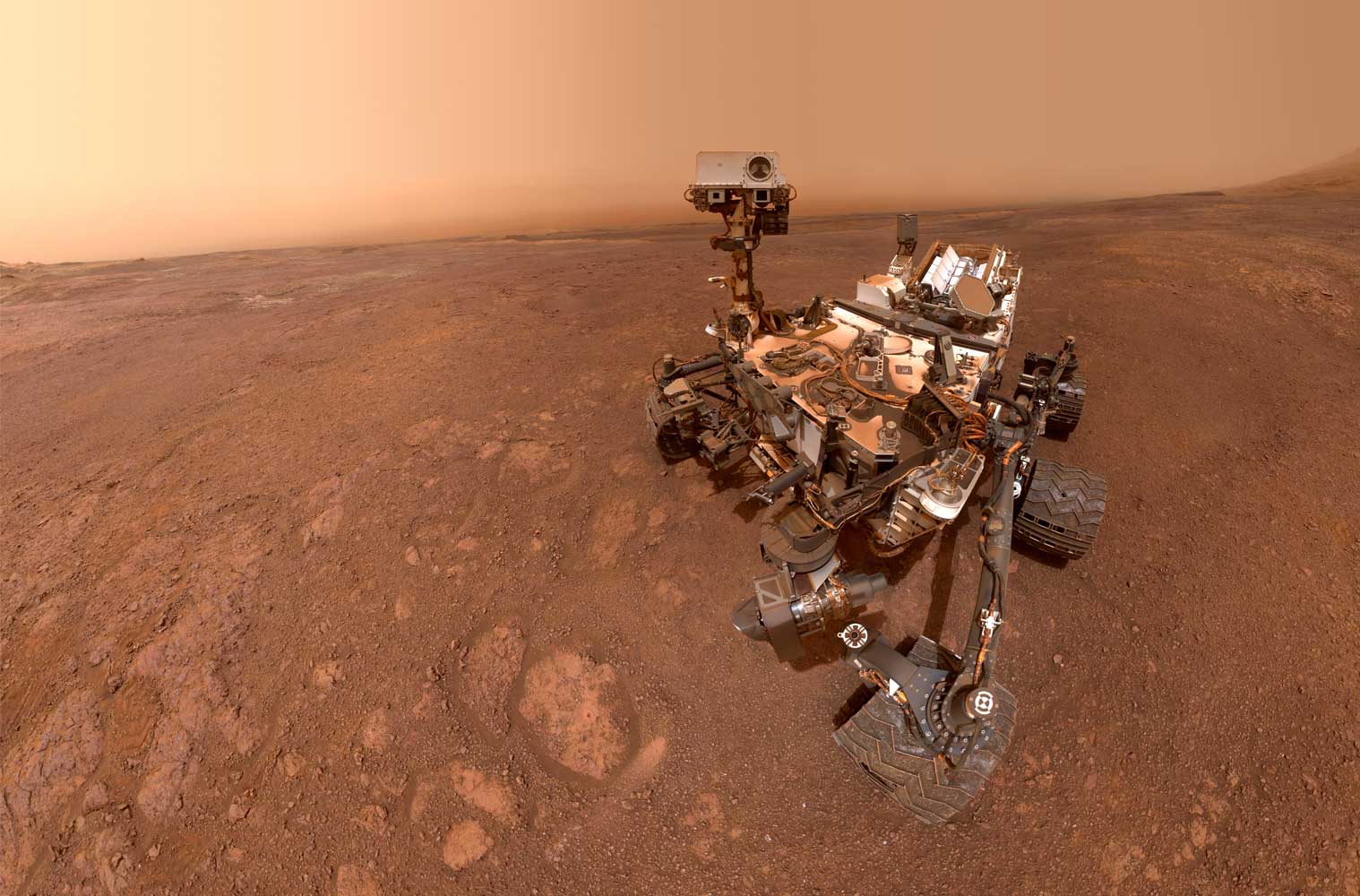 The Curiosity Mars rover sits on the dusty red surface of Mars.