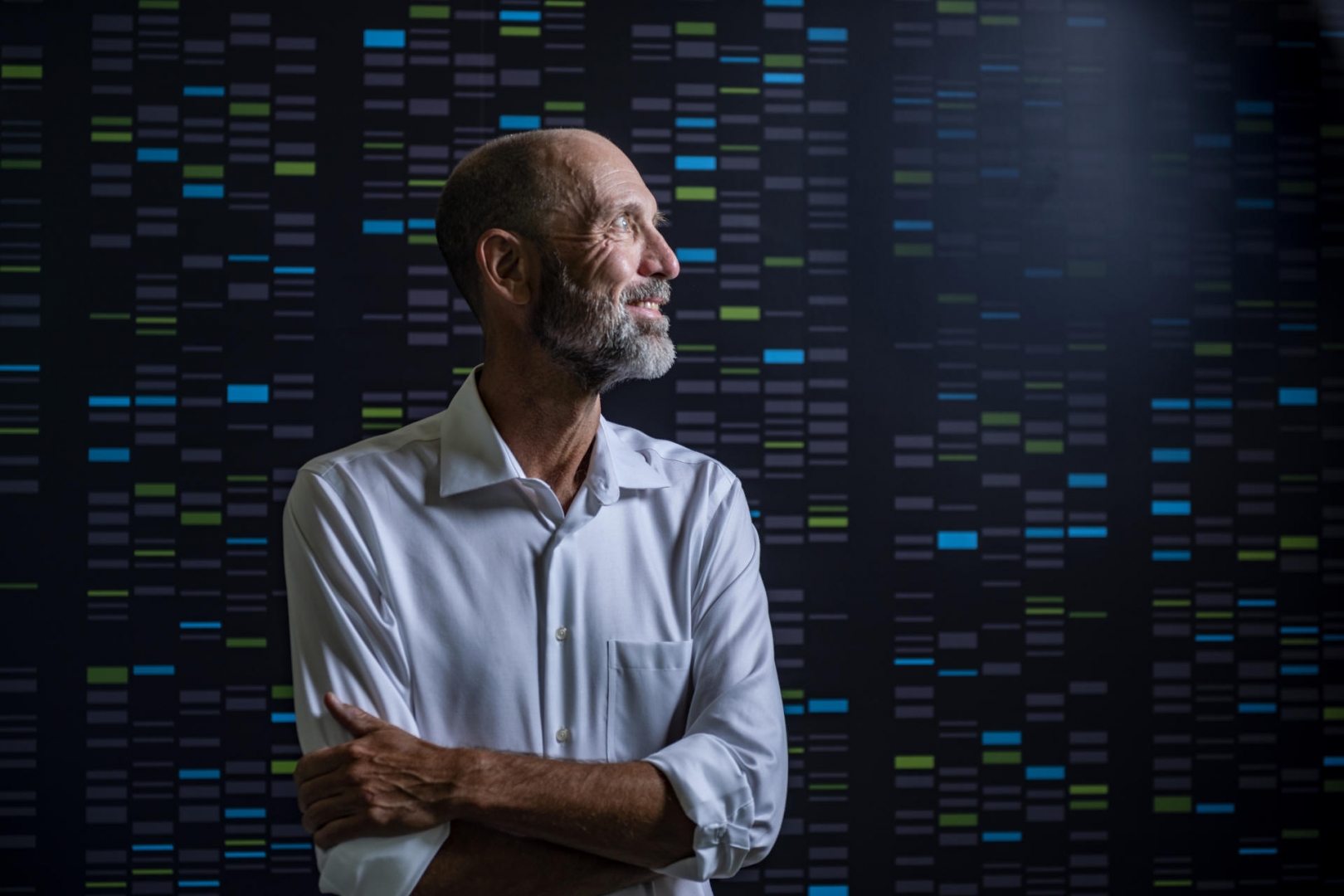 Portrait of Mark Velligan against a wall that shows the coding lines of DNA sequencing.
