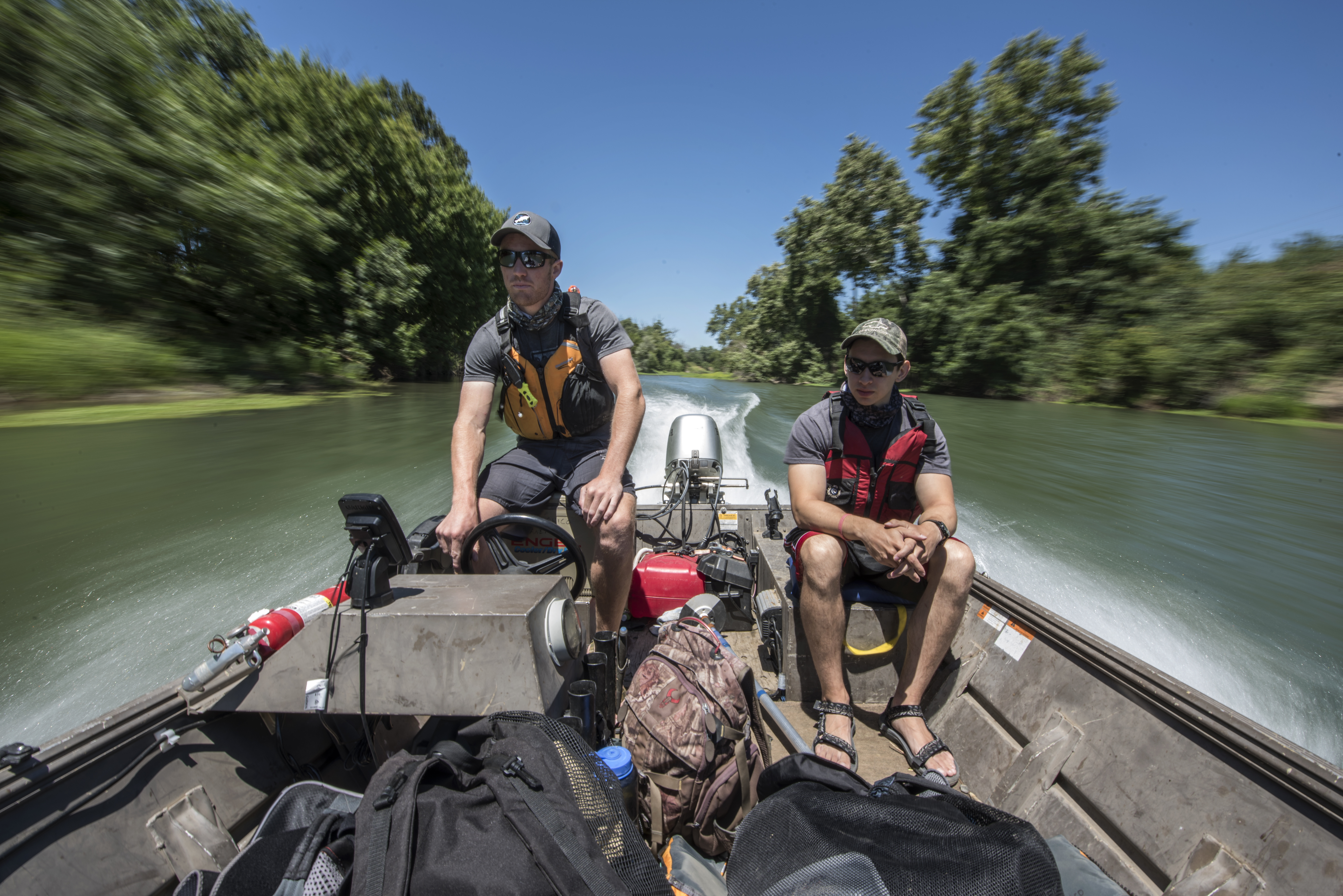 Graduate student Dylan Stompe (left) drives a boat along with Carlos Estrada (right) as students count salmon as part of a Summer Undergraduate Research Program (UGR) involved in the Chico STEM Connections Collaborative (CSC2) program on the Sacramento River on Wednesday, July 5, 2017 in Chico, Calif. (Jason Halley/University Photographer)