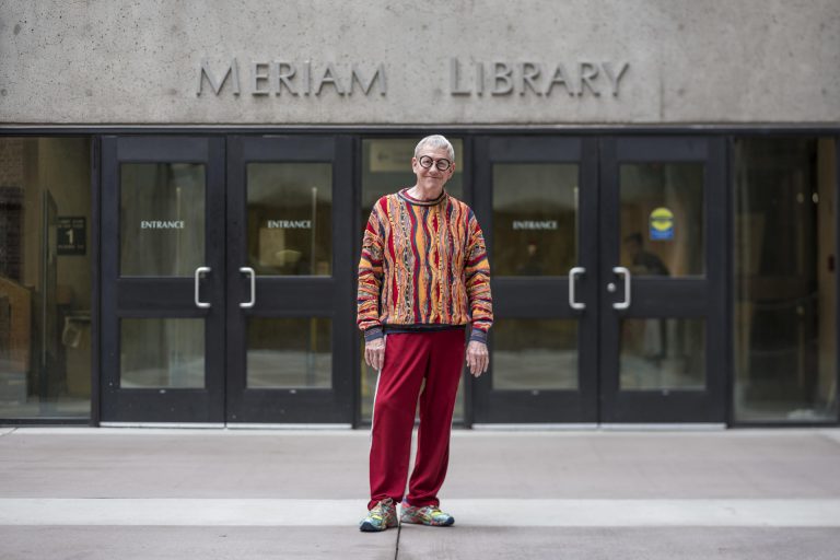 Joe Crotts posing for a photo in front of the "Meriam Library" sign in front of the library entrance.
