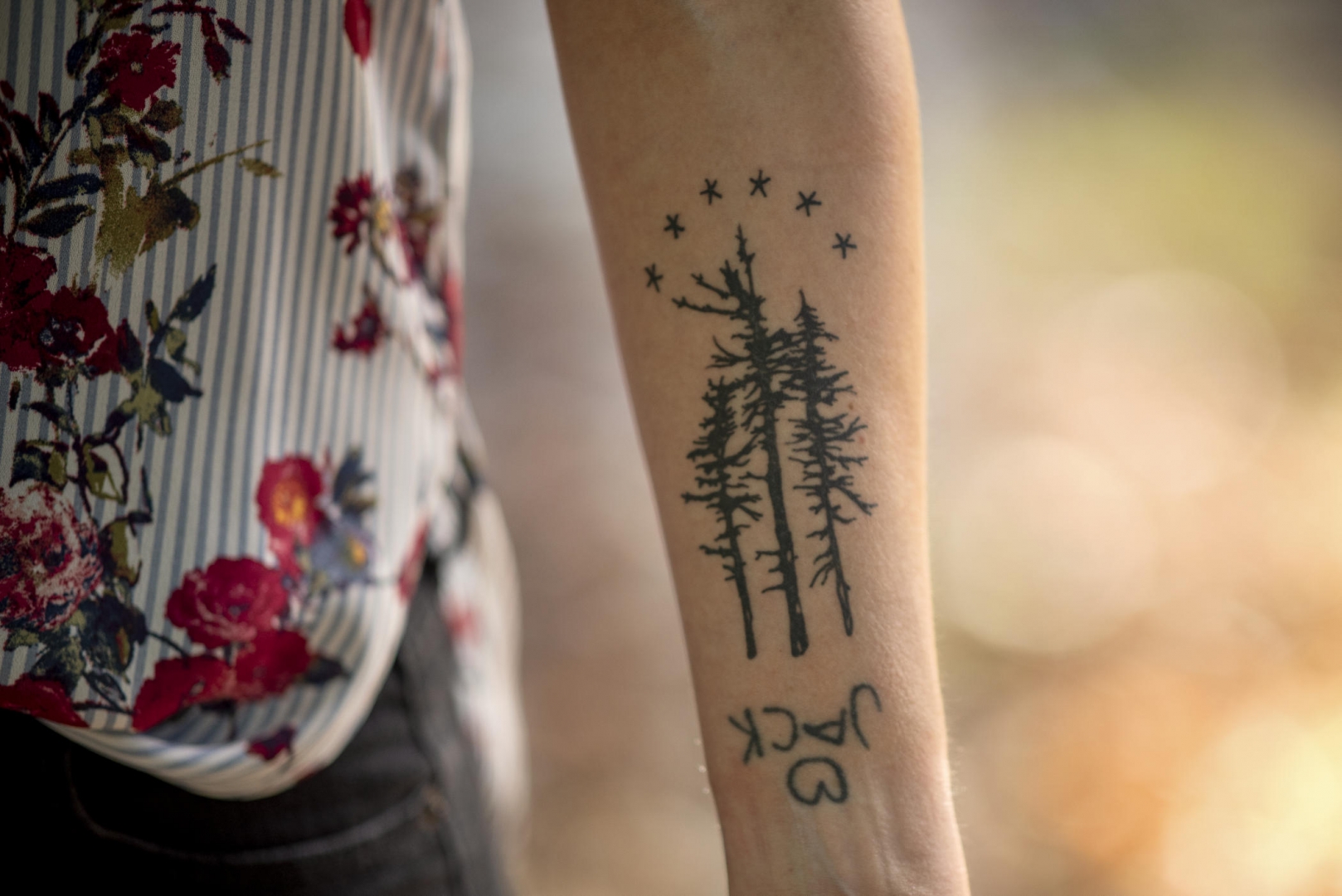 A tattoo on Tamara Bradford's forearm has thee pine trees, the word Jack with a heart above it, and six stars.