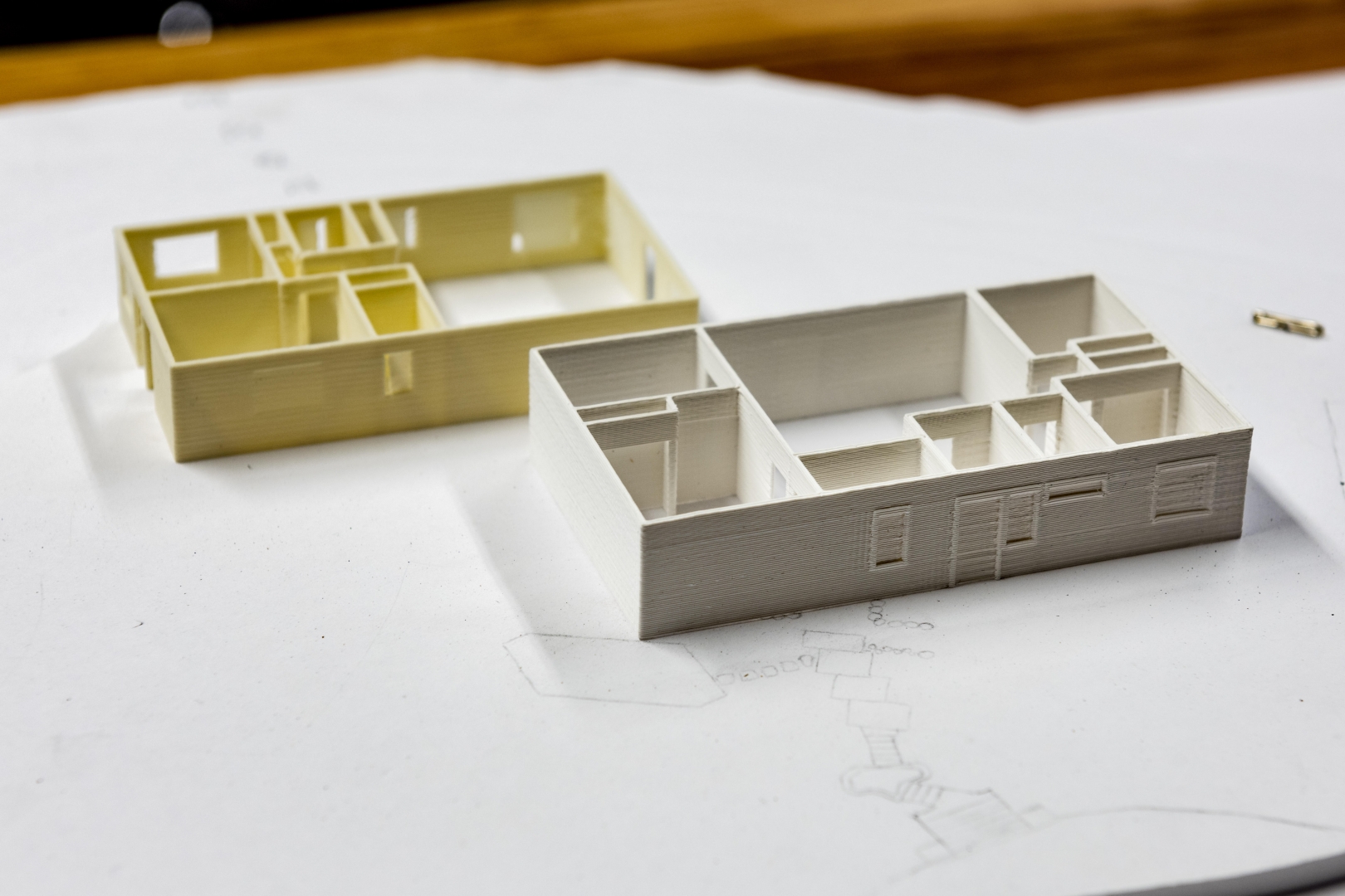 3D models of houses are sitting on a piece of paper that has landscaping drawn onto it.