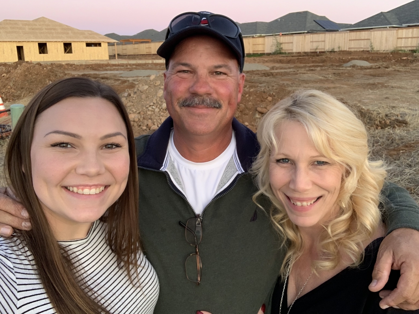 Kelsea Kennedy poses for a selfie with her dad and mom at the build site for their new home.