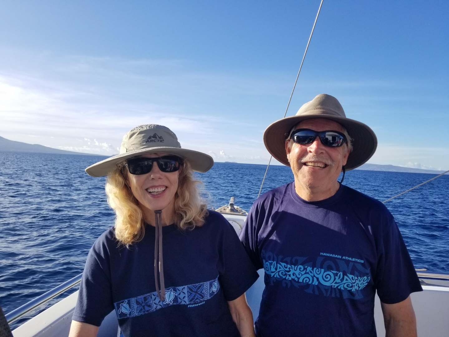 Cindy Wolff and her husband smile on a boat off the coast of Maui, with the ocean stretching behind them.