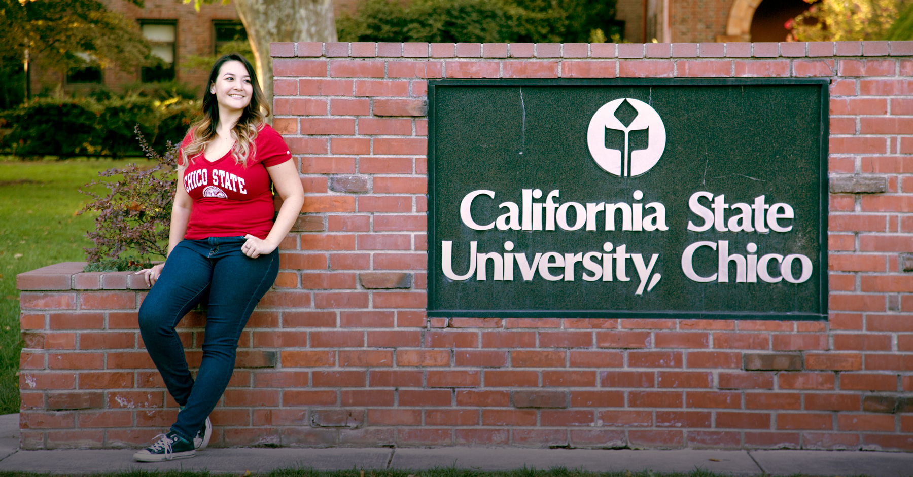 Student poses next to the California State University, Chico, sign.