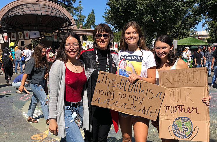 President Hutchinson stands with students holding signs calling for action against climate change at a strike in city plaza.