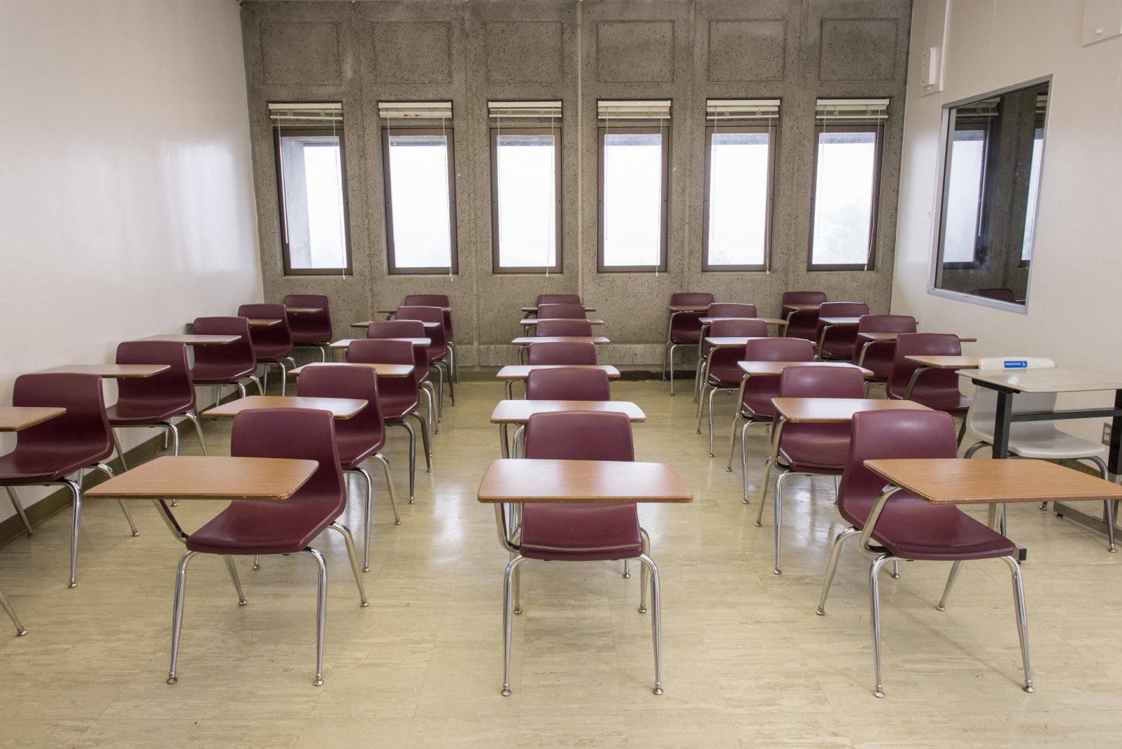 Rows of desks are lined up inside a classroom.