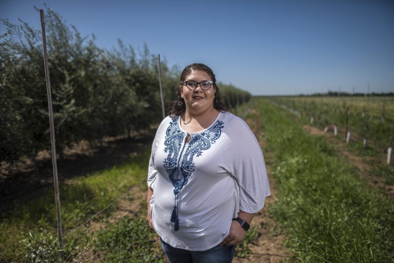 Stephanie Alvarado stands next to an olive orchard at the University Farm