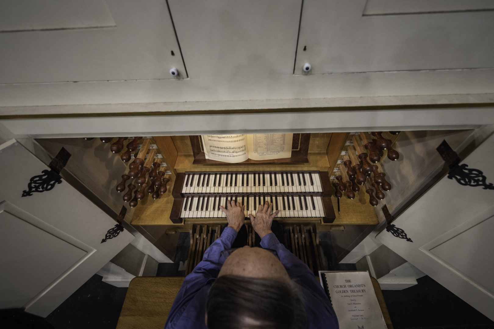 An overhead view of a man playing the organ keyboard.
