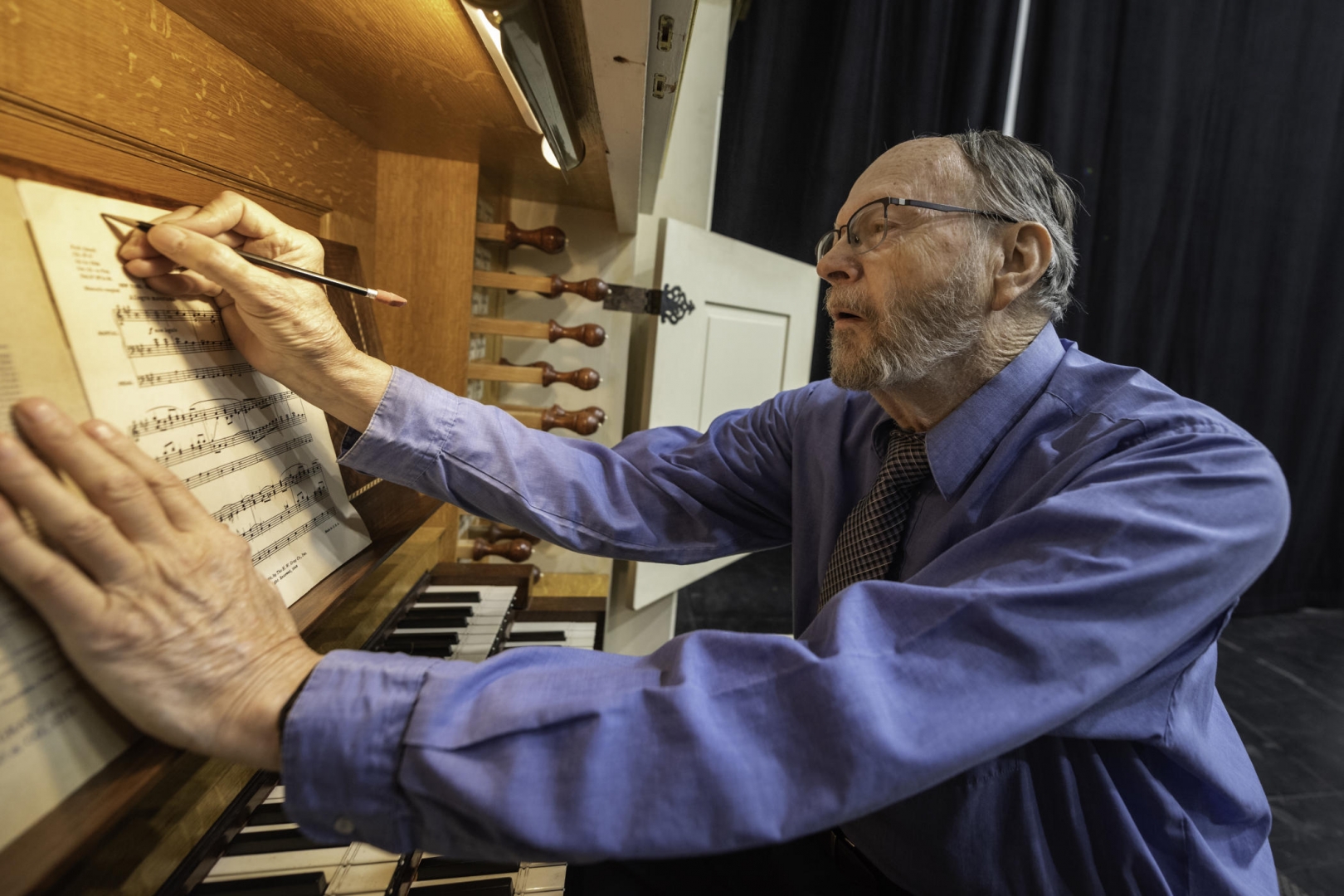 David Rothe makes notes on a sheet of music while seated at the organ keyboard.