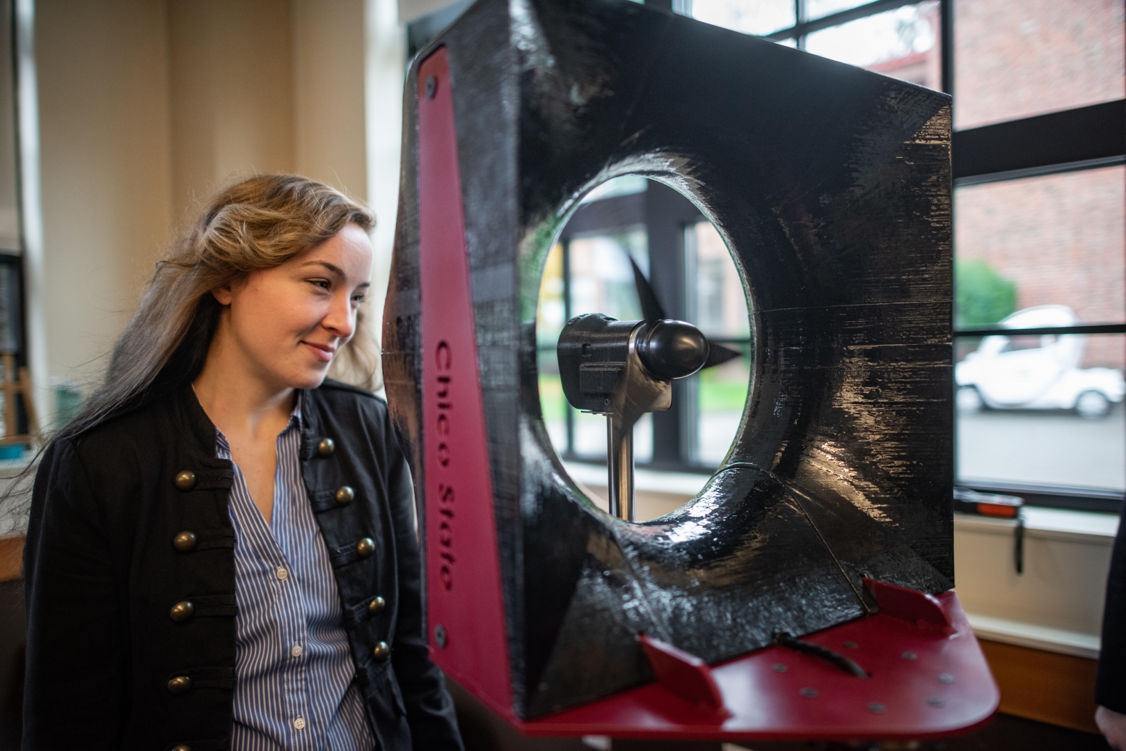 Kate Gordon looks into a wind tunnel as it blows her hair back.