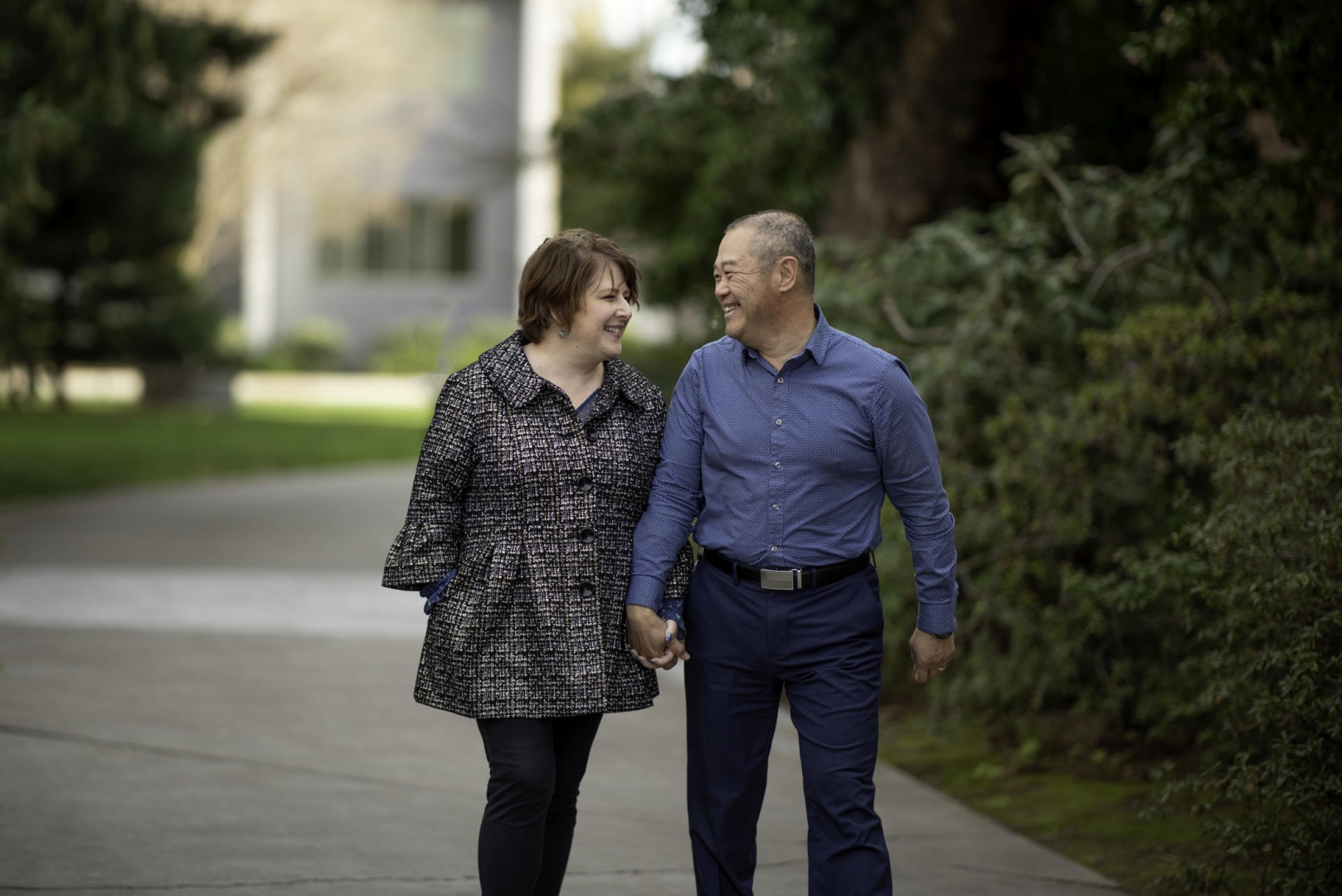 Terry Quinto and Ray Quinto walk down a campus path holding hands.