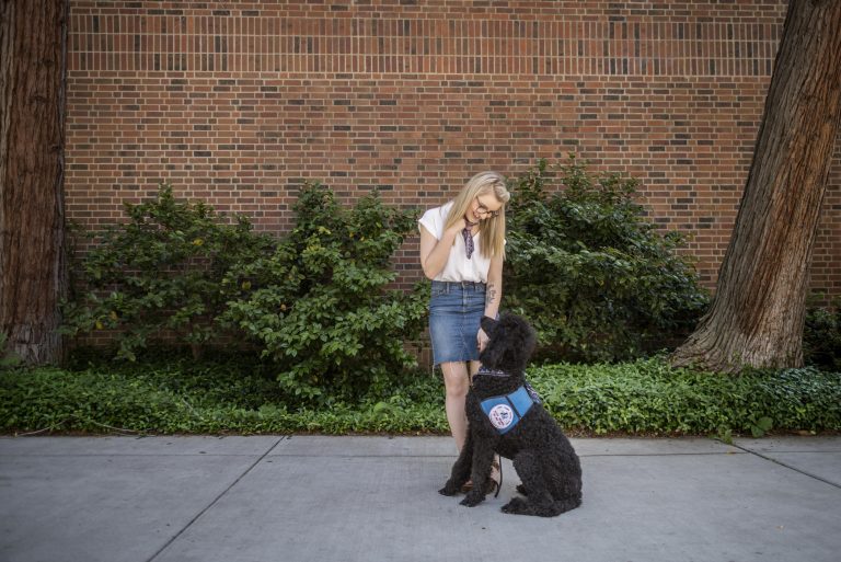 Taylor Coutts looks down at her service dog Davy