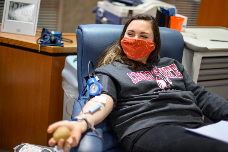 Anna Paladini smiles behind a mask as she gives blood.