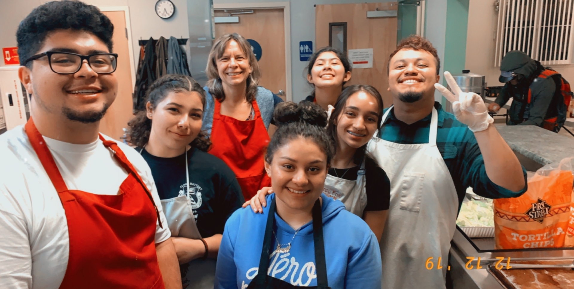 Enrique Galvan and a group of students pose for a picture at a homeless shelter after working in the kitchen.