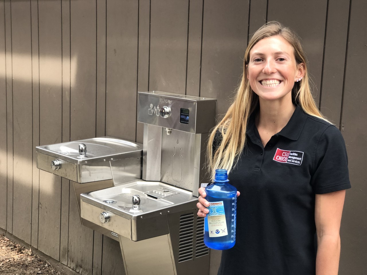 MacKenzie Deeter poses with a reusable water bottle near the water filling stations.