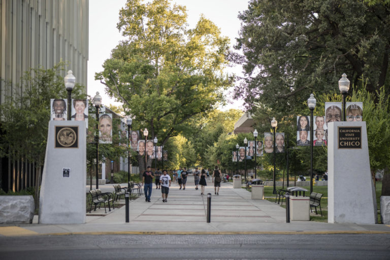 The southeast entrance to campus shows the faces of students, faculty, and staff on pole banners.