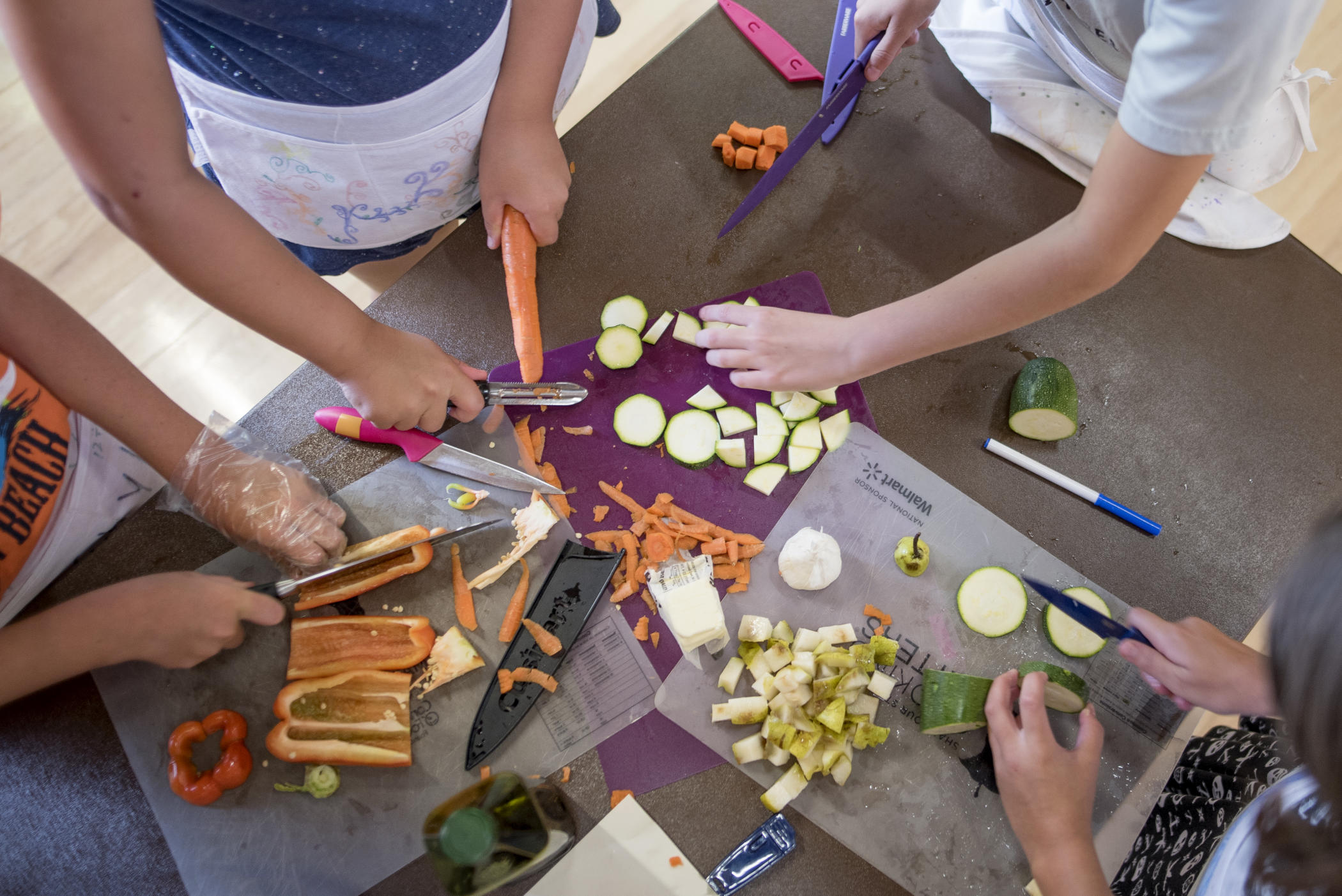 Overhead view of children chopping vegetables on cutting boards