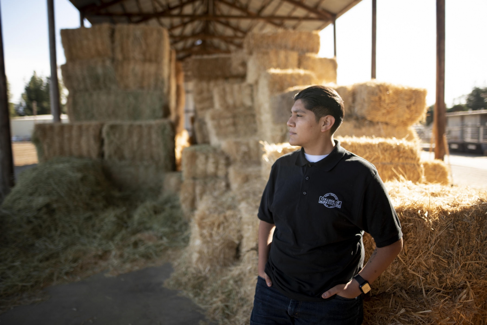 Jonathan Najera stands by some bales of hay.
