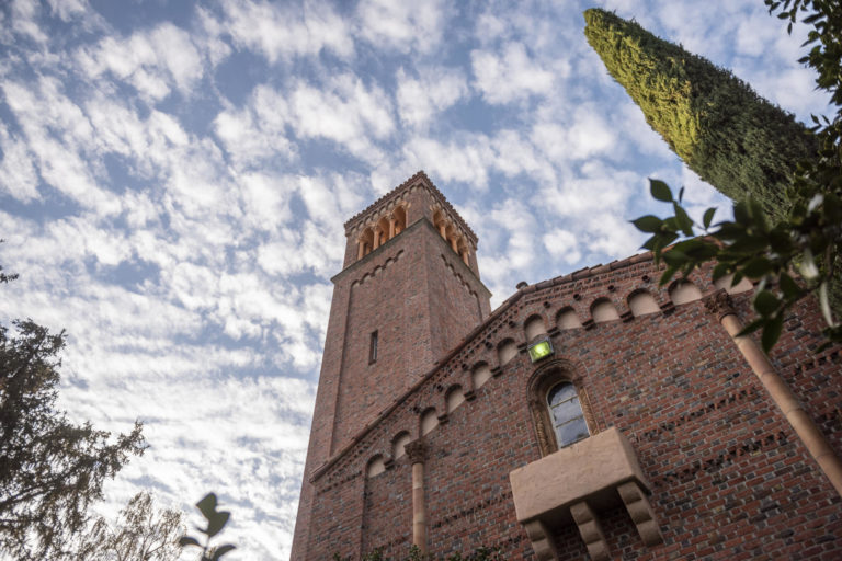 White puffy clouds float slowly above the Trinity Bell Tower in October 2018
